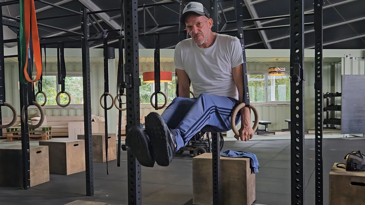 Chris (54): sterker worden na je 50e ondanks jarenlange schouderklachten Chris voert een L-sit uit aan de ringen tijdens een krachttraining bij Naudiz
