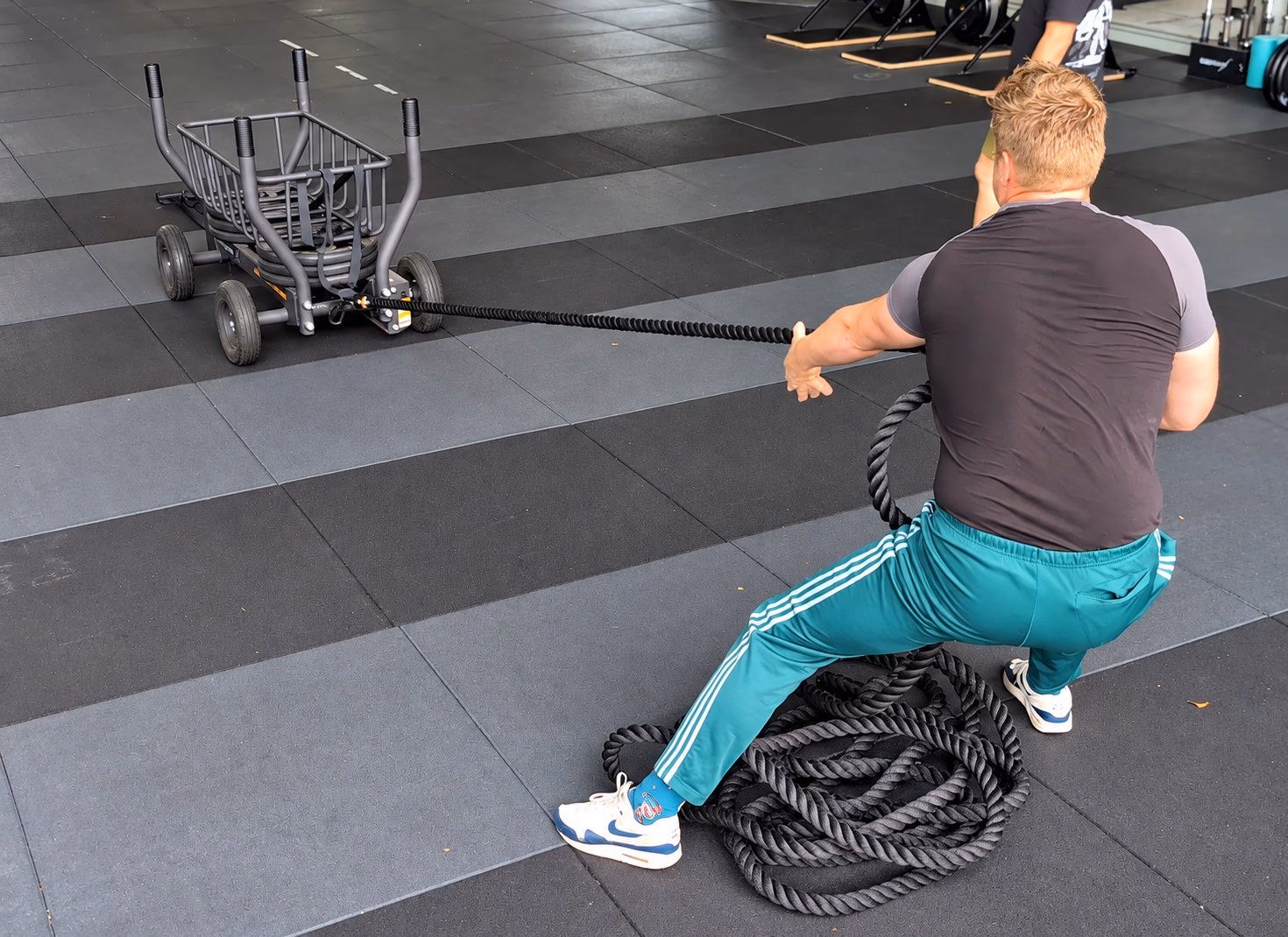 Jay (32): van trainingsplateau naar nieuwe persoonlijke records Jay trekt met een dik touw een trainingsslee op wielen naar zich toe bij Naudiz.